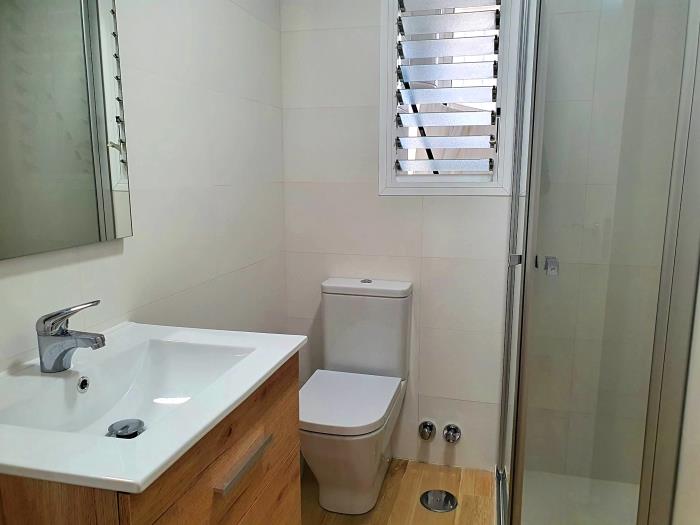 Family bathroom with walk-in shower, sink with mirror, and toilet